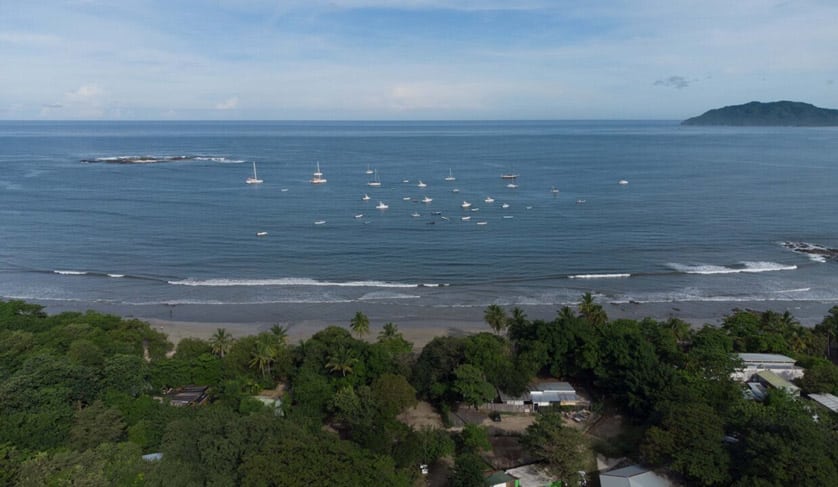 Aerial view of a beachfront property in a tropical setting with boats and clear waters